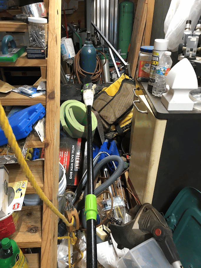 Cluttered garage storage area filled with tools, cords, and workshop supplies